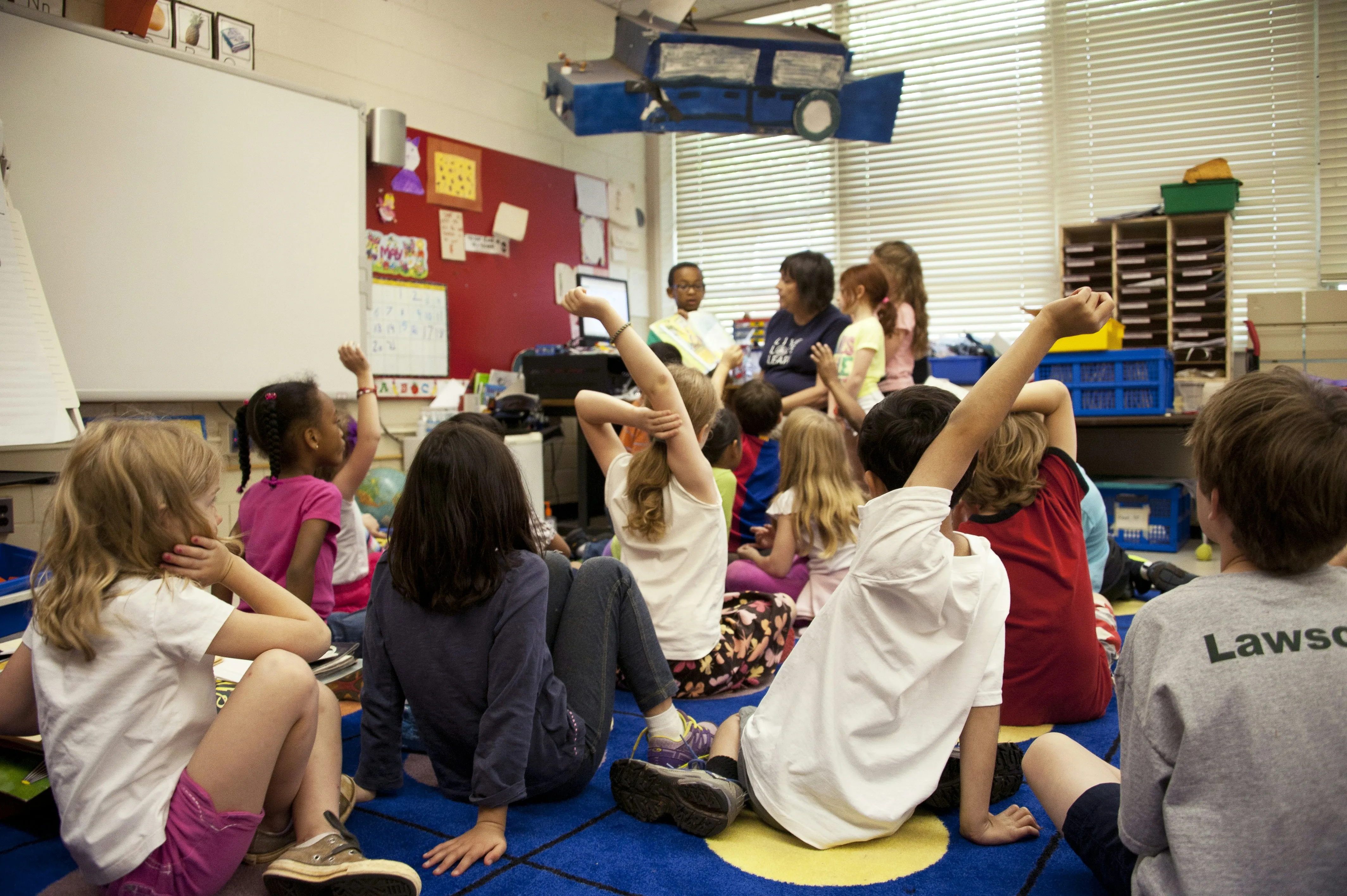 children raising their hands in a classroom
